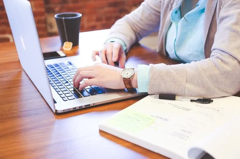 woman-sitting-at-table-and-using-laptop-with-tea-cup-in-background