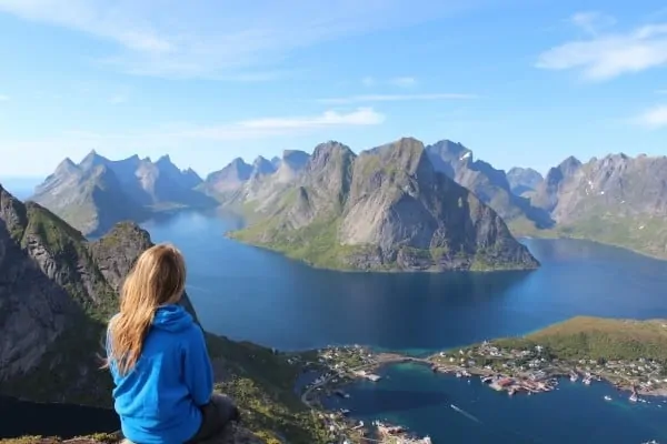 young-blonde-woman-sitting-on-rock-and-looking-at-mountains-and-lake